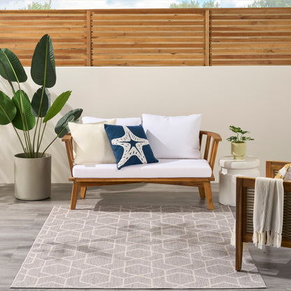 Modern 5' x 7' geometric outdoor rug in a coastal patio setting with plants.