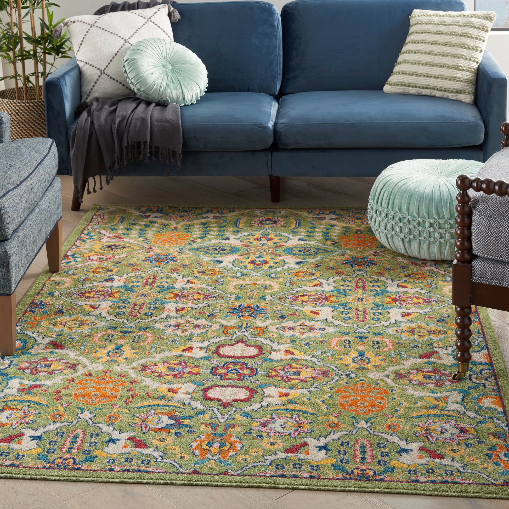 Colorful patterned rug with a green border under a blue sofa, paired with a mint pouf and striped cushions.