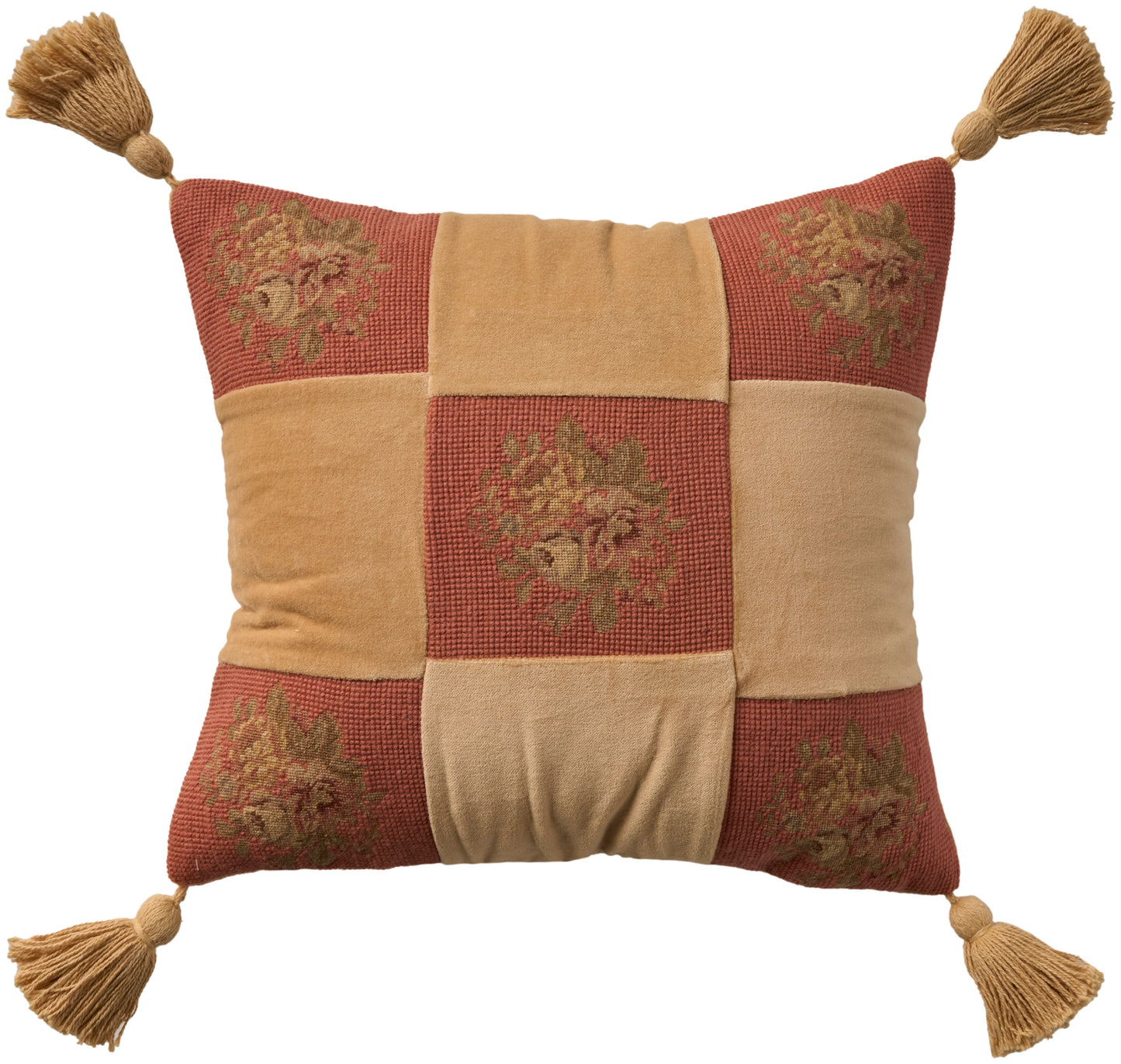 Decorative patchwork pillow in orange and tan squares with floral embroidery and tassels at each corner.