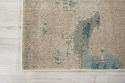 Beige textured area rug with turquoise abstract blotches on light wood floor; modern decor.