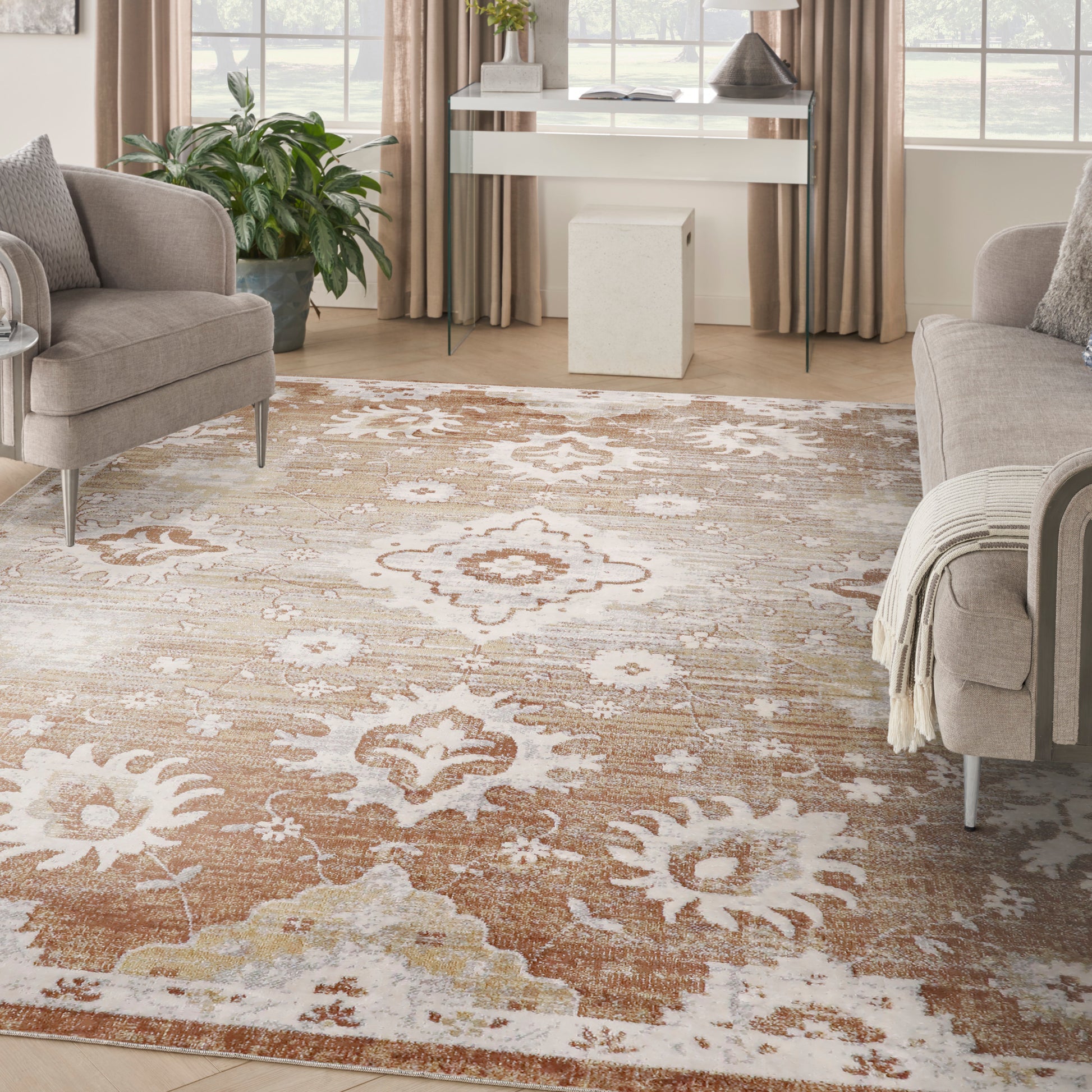 Neutral-toned oriental rug in beige, cream, and brown over wood floor, flanked by gray sofas in a bright living room.