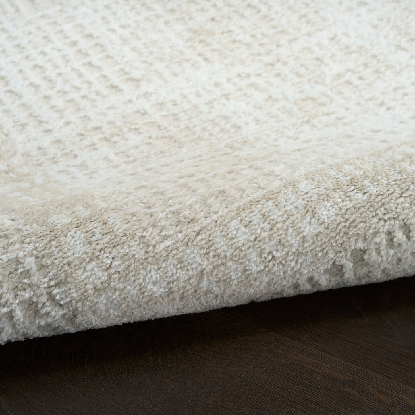 Cream shag rug with dense microfiber pile, close-up showing soft plush texture on dark wood floor.