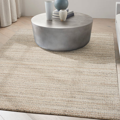 Round gray concrete coffee table on a beige textured rug; vases and books on top.