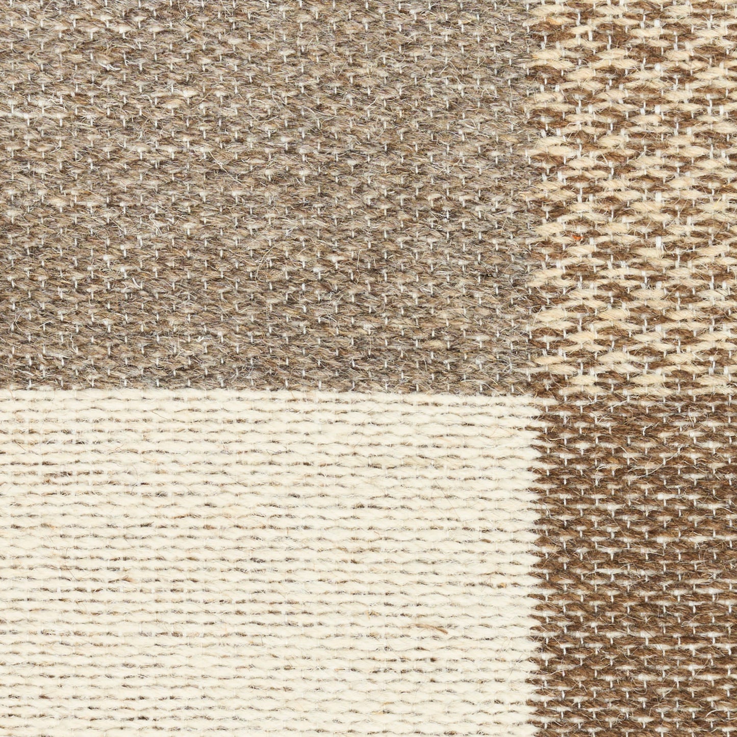 Neutral patchwork rug in beige, taupe, & cream with textured woven stripes and natural fibers.