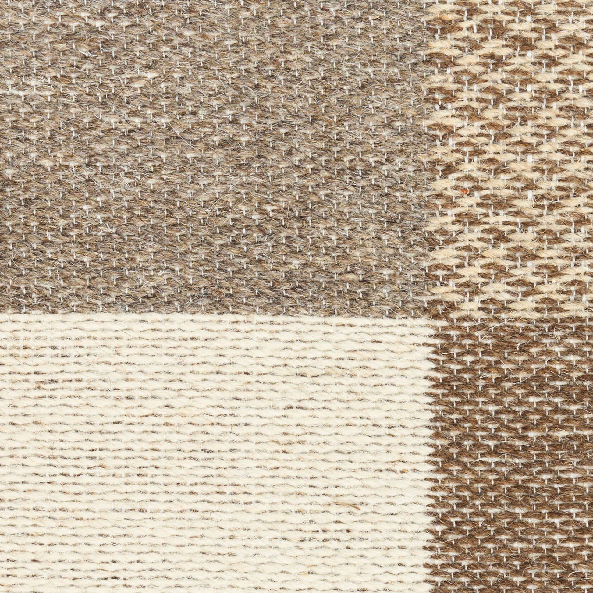 Neutral patchwork rug in beige, taupe, & cream with textured woven stripes and natural fibers.
