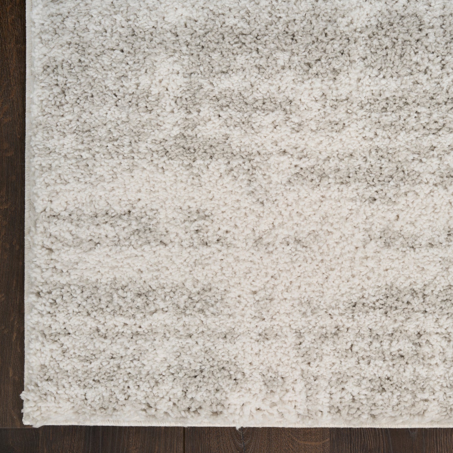 Cream shag area rug with dense plush pile on dark wood floor, rectangular and cozy for living spaces.