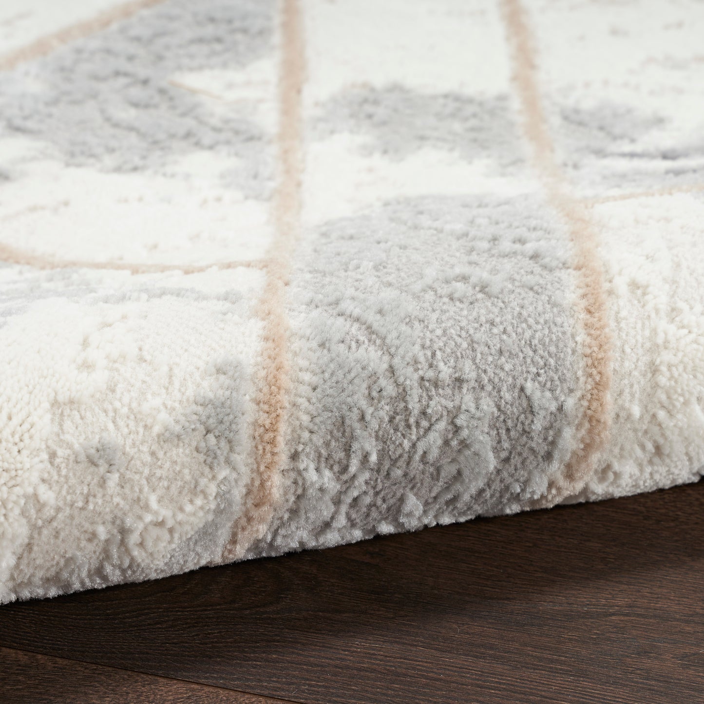 Cream and light gray plush area rug with tan grid lines, soft high-pile on dark wood floor.