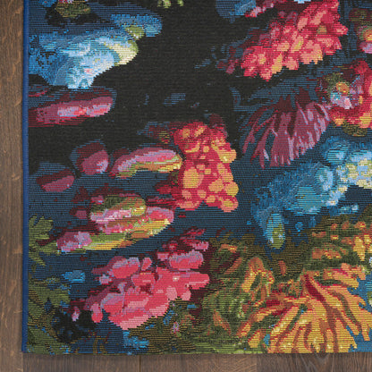 Colorful floral tapestry rug with a dark background, blue edge, and vivid pink, red, yellow flowers on a wooden floor.