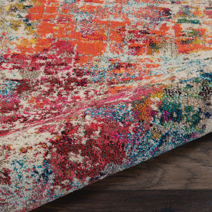 Close-up of a plush multicolor area rug with an abstract pattern in red, orange, pink, blue and cream on dark wood floor.