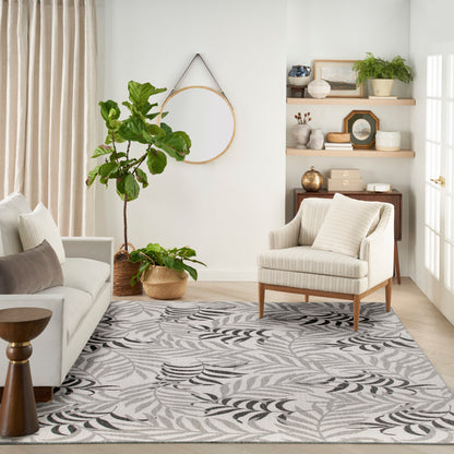 Neutral living room with beige sofa, striped chair, leaf-pattern rug, tall fiddle-leaf fig in wicker basket, round wall hoop.