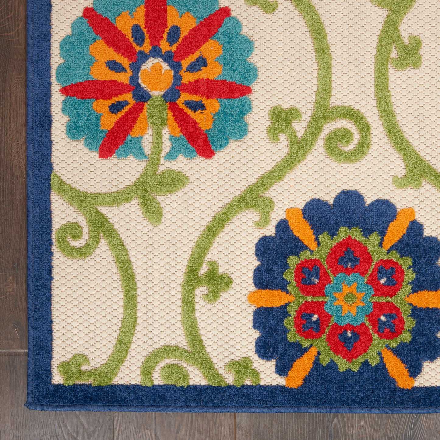 Decorative area rug with two bold floral medallions in blue, red and orange on cream with green vines and navy border.