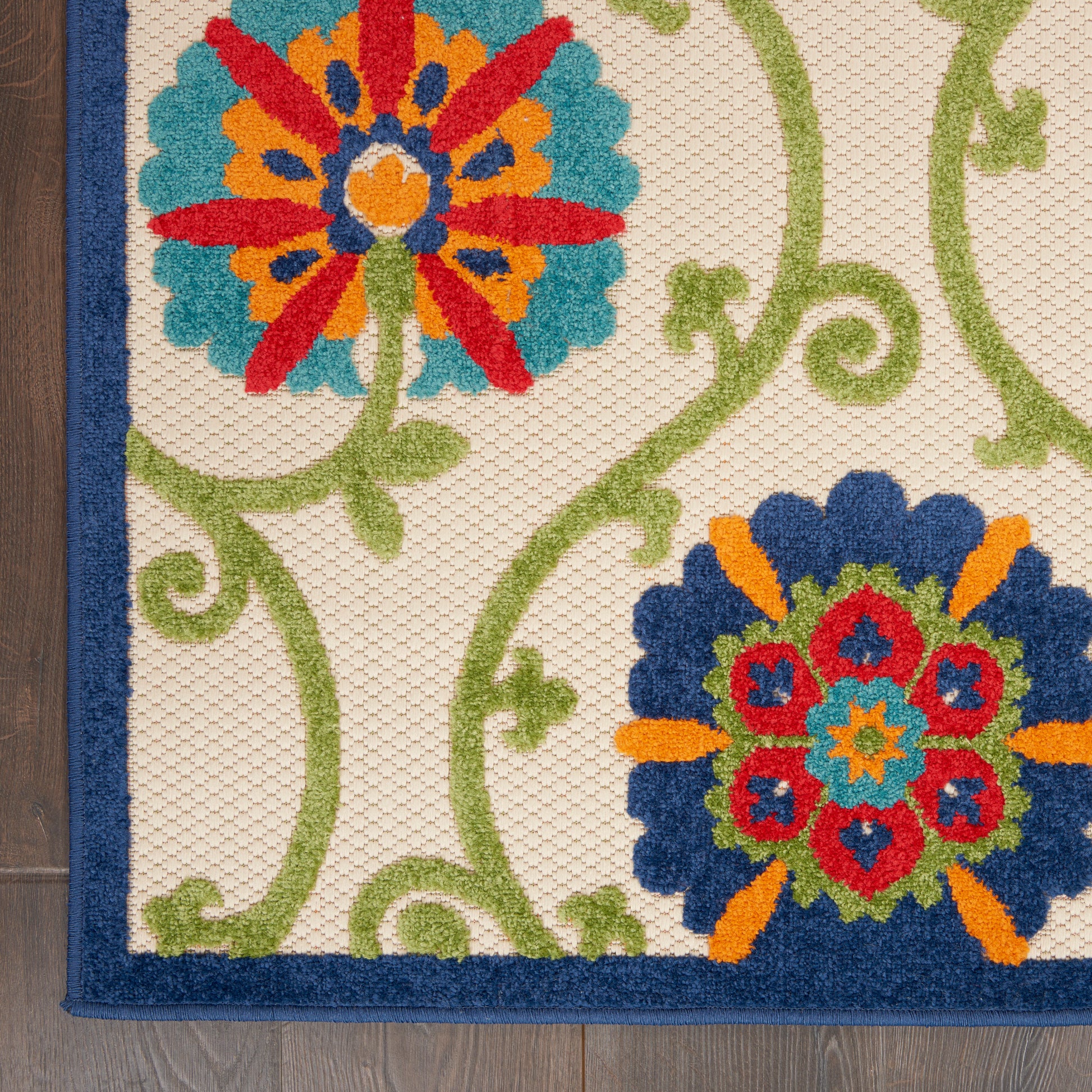 Decorative area rug with two bold floral medallions in blue, red and orange on cream with green vines and navy border.