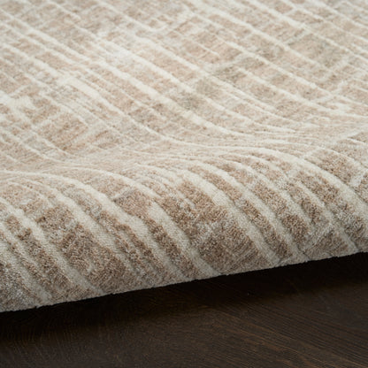 Beige textured rug with a wavy geometric pattern and plush pile on dark wood floor.