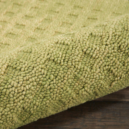 Olive-green shaggy rug close-up with dense looped pile on dark wooden floor.
