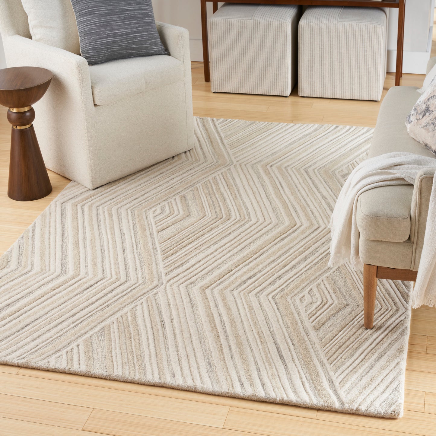 Neutral cream and beige chevron rug with textured stripes on light wood flooring in a bright living room.
