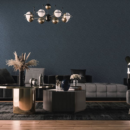 Modern living room with navy wall, plaid sectional sofa, gold and gray coffee tables, globe chandelier, dried pampas grass.