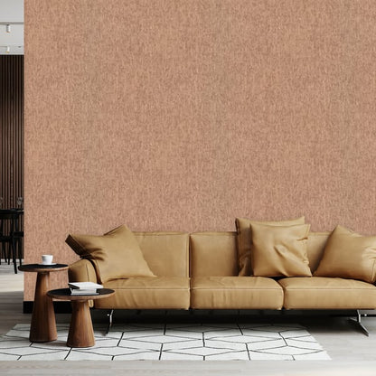 Tan leather sofa with square cushions on slender metal legs, peach textured wall, round wooden side tables, geometric rug.