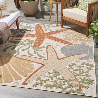 Outdoor coastal rug with orange and beige starfish and green seaweed pattern on a patio with wicker furniture.