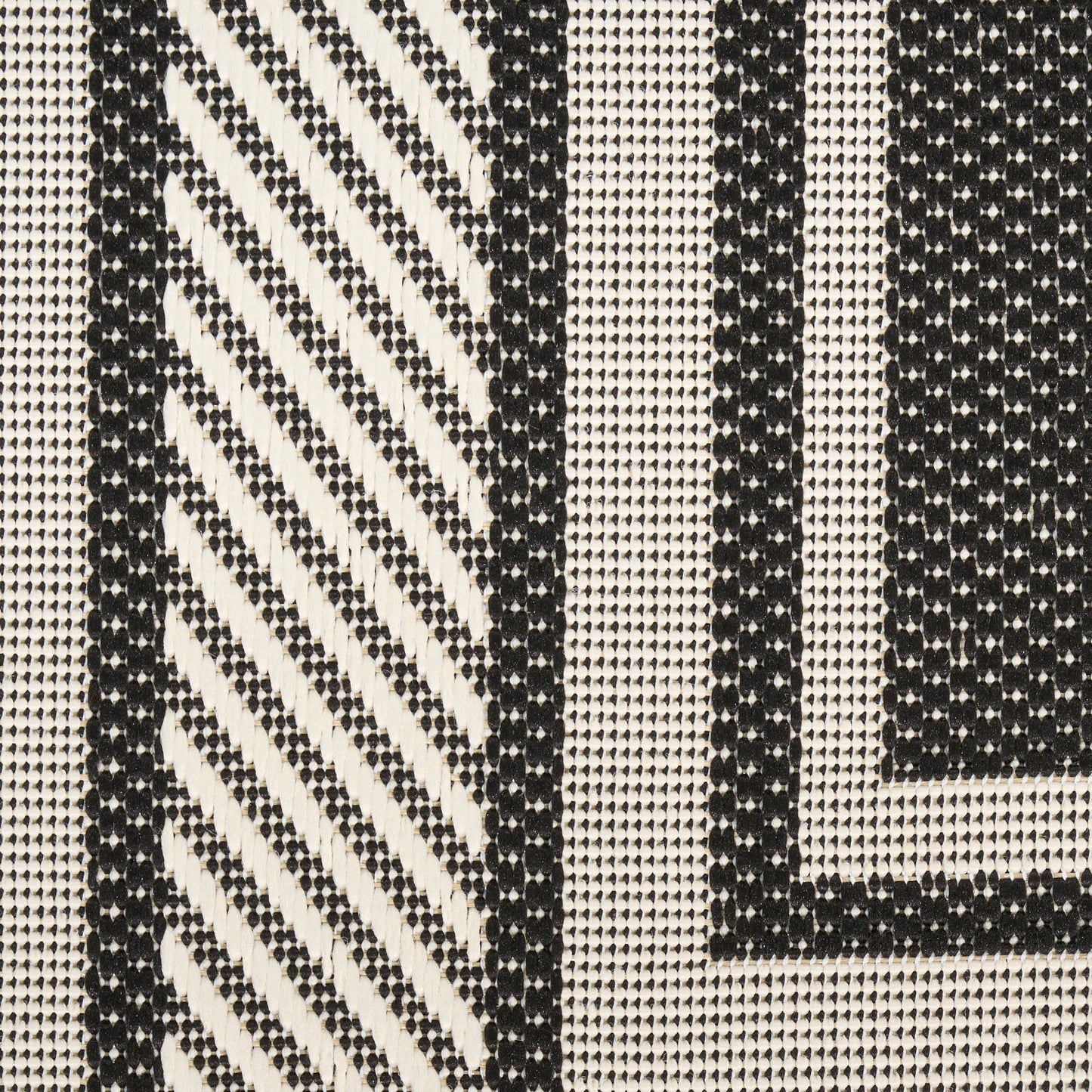 Black and cream woven rug with bold geometric stripes and diagonal hatch pattern, jacquard-style weave.