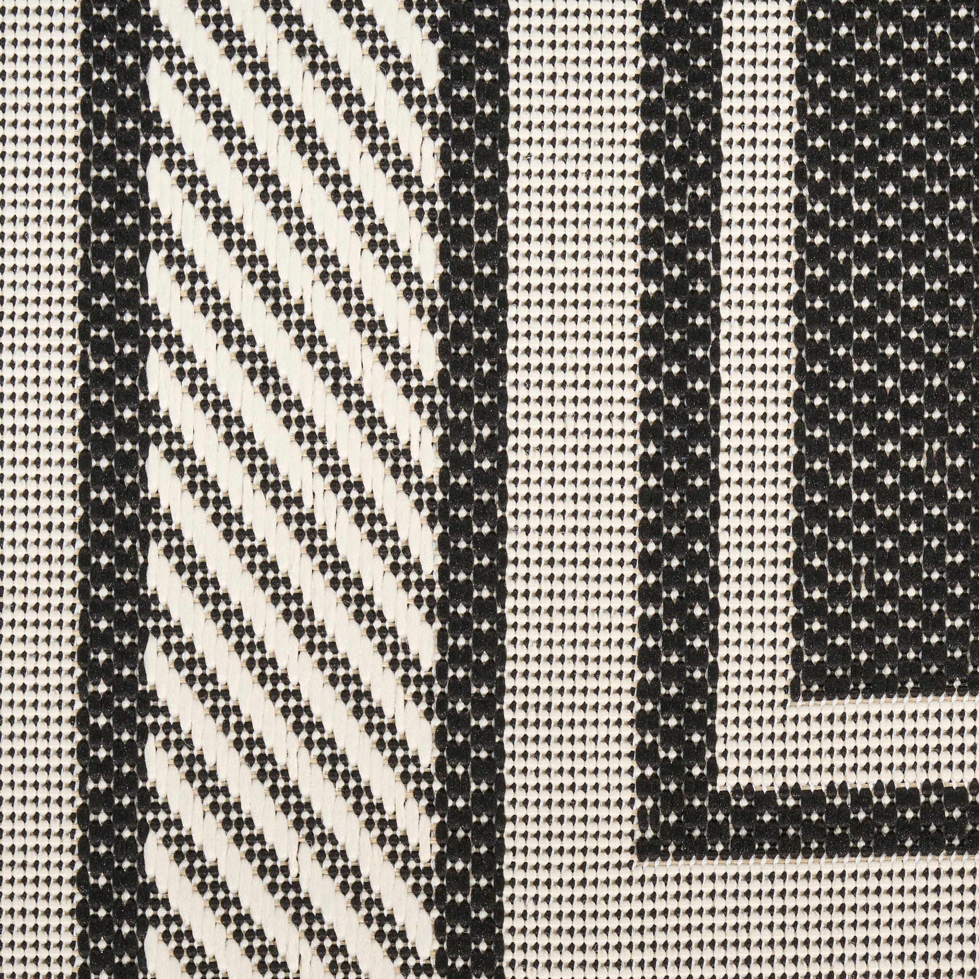 Black and cream woven rug with bold geometric stripes and diagonal hatch pattern, jacquard-style weave.
