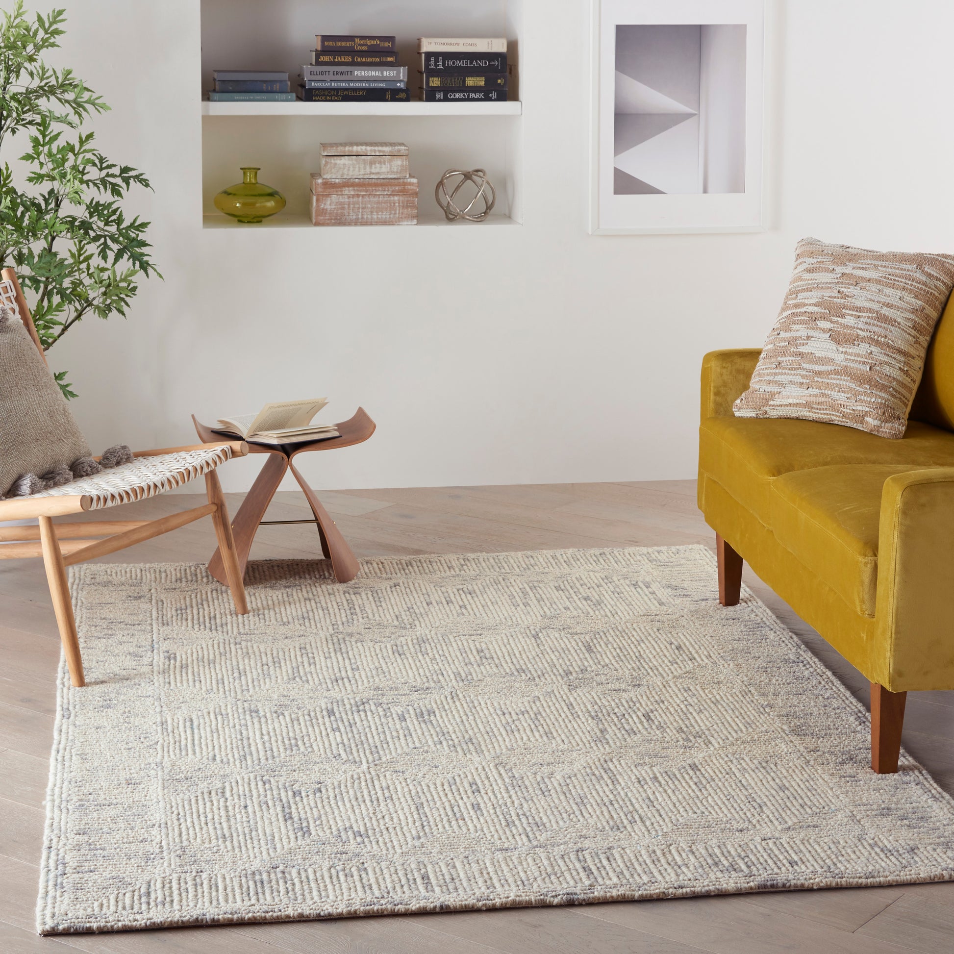 4' x 6' beige geometric rug in a living room with a mustard velvet sofa, mid-century chair, small wood coffee table and a plant.