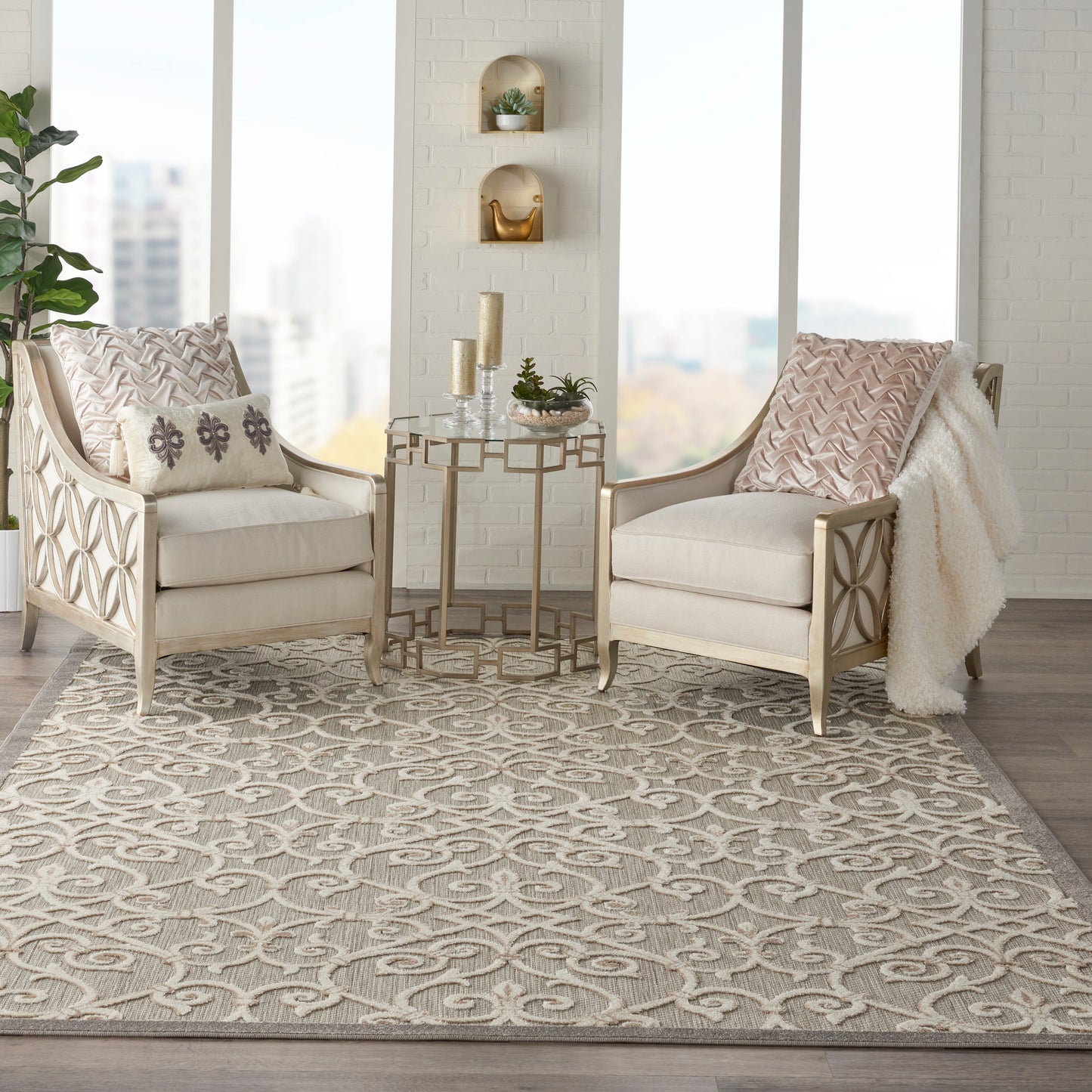Neutral living room with two beige chairs, lattice wood frames, a gold side table, patterned pillows, and a gray geometric rug (8' x 11').