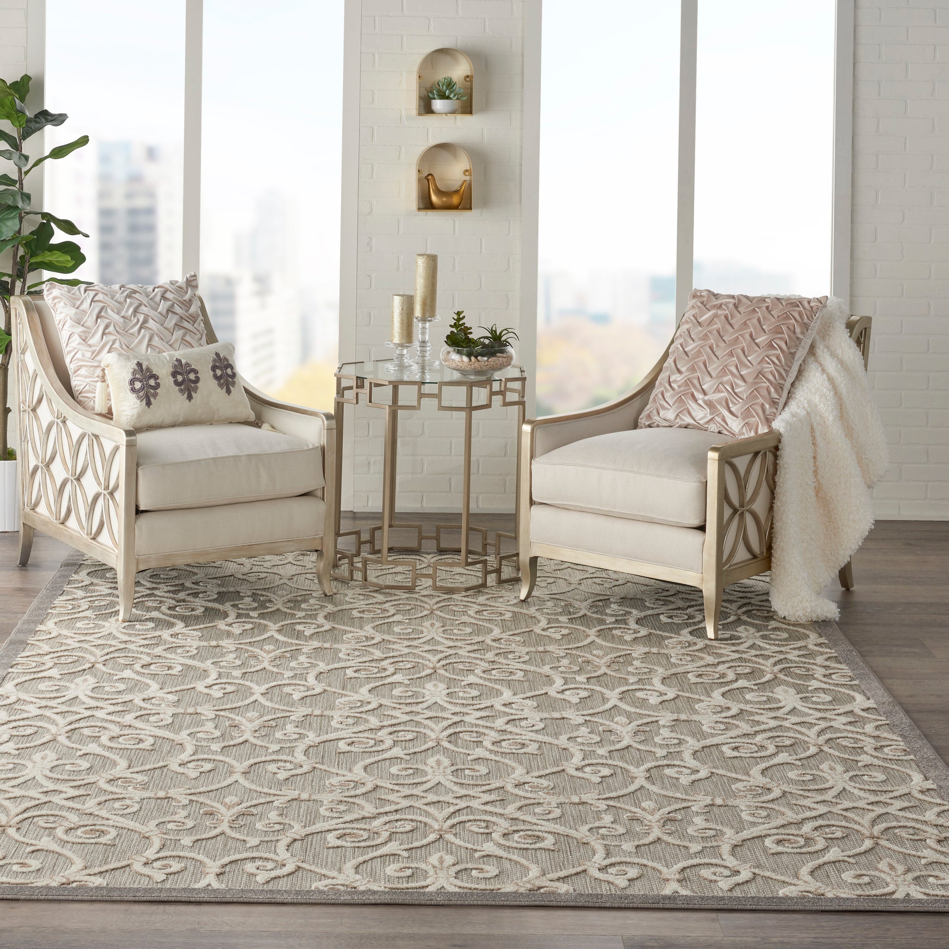 Neutral living room with two beige chairs, lattice wood frames, a gold side table, patterned pillows, and a gray geometric rug (8' x 11').