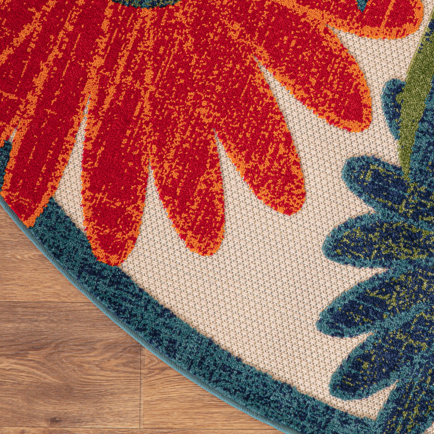 Vibrant floral rug with orange-red petals and teal border on beige backdrop; two gradient color swatches on hardwood floor.