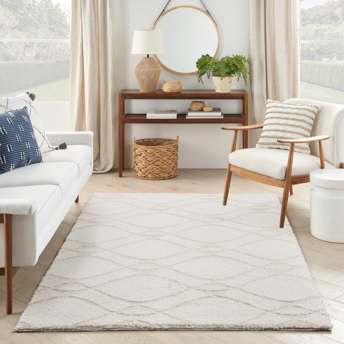 Ivory shag rug with a subtle geometric pattern in a bright Scandinavian living room; white sofa, wooden chair, woven baskets, greenery