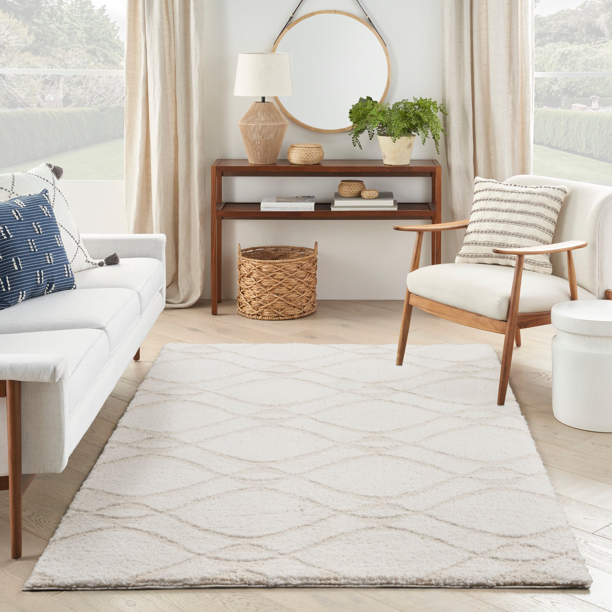 Ivory shag rug with a subtle geometric pattern in a bright Scandinavian living room; white sofa, wooden chair, woven baskets, greenery