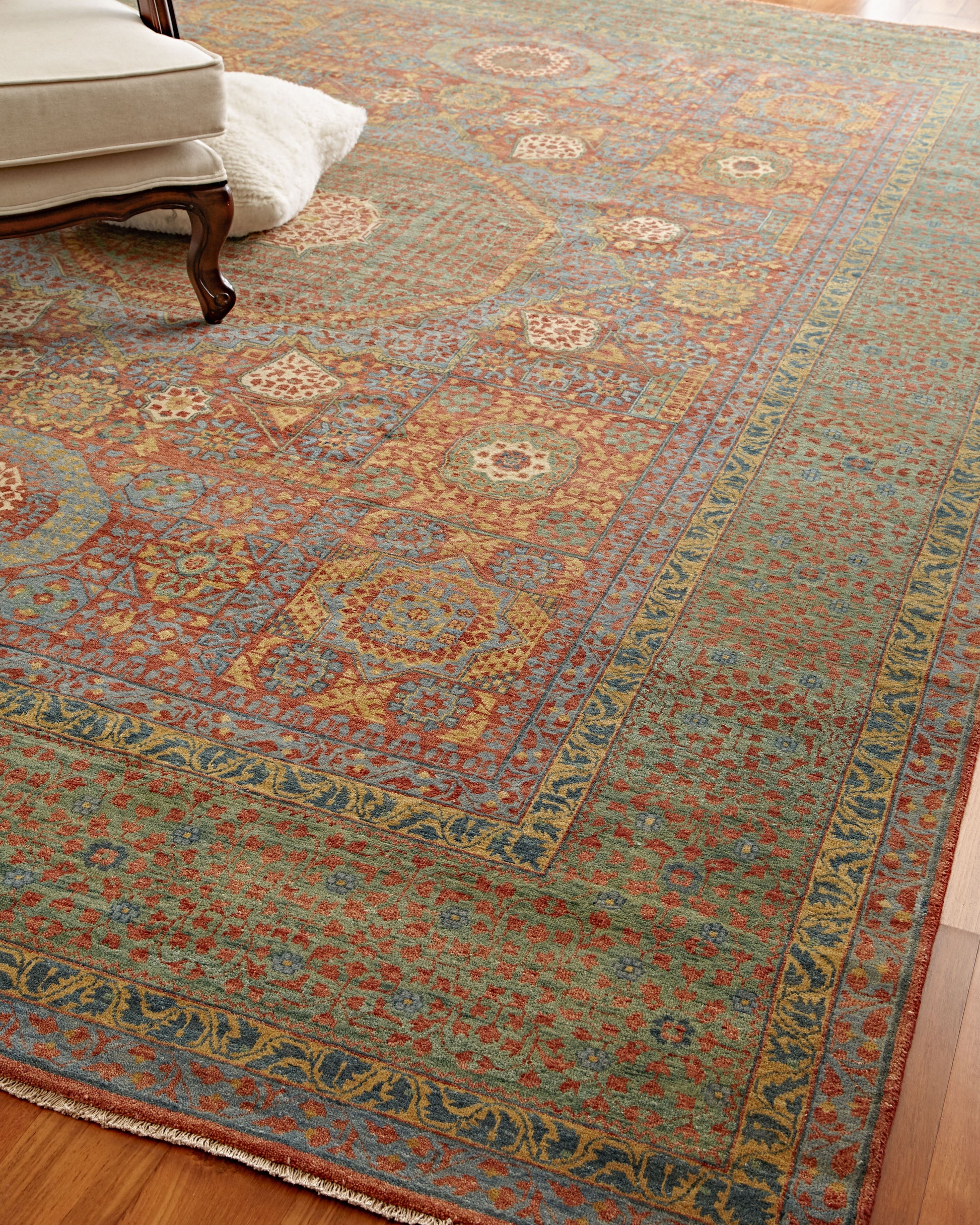 Large wool oriental rug with teal field, red and gold floral motifs, blue borders and fringed edge.