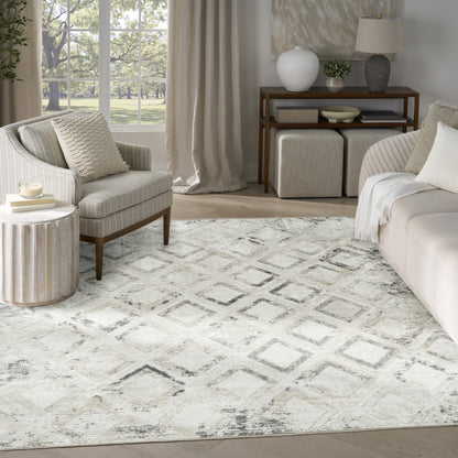 Neutral living room with cream sofa, beige armchair, diamond rug, light wood furniture and large window with greenery.