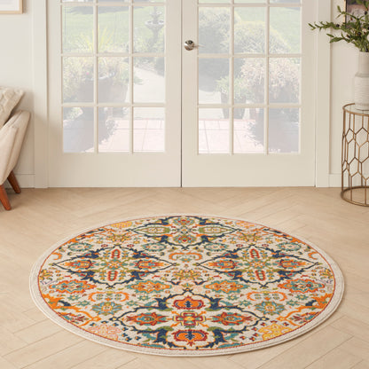 Round bohemian rug with multicolored floral medallions in orange, teal, blue and cream; on light wood floor by French doors.