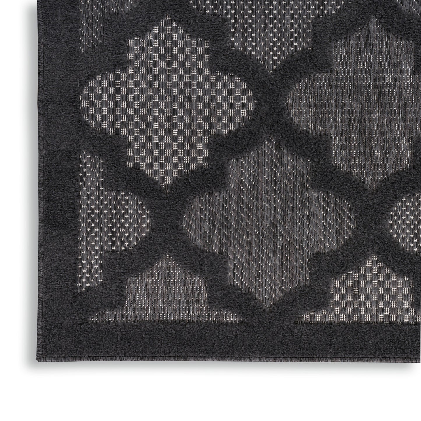 Close-up of a dark charcoal rug with a raised geometric trellis pattern in lighter gray tones.