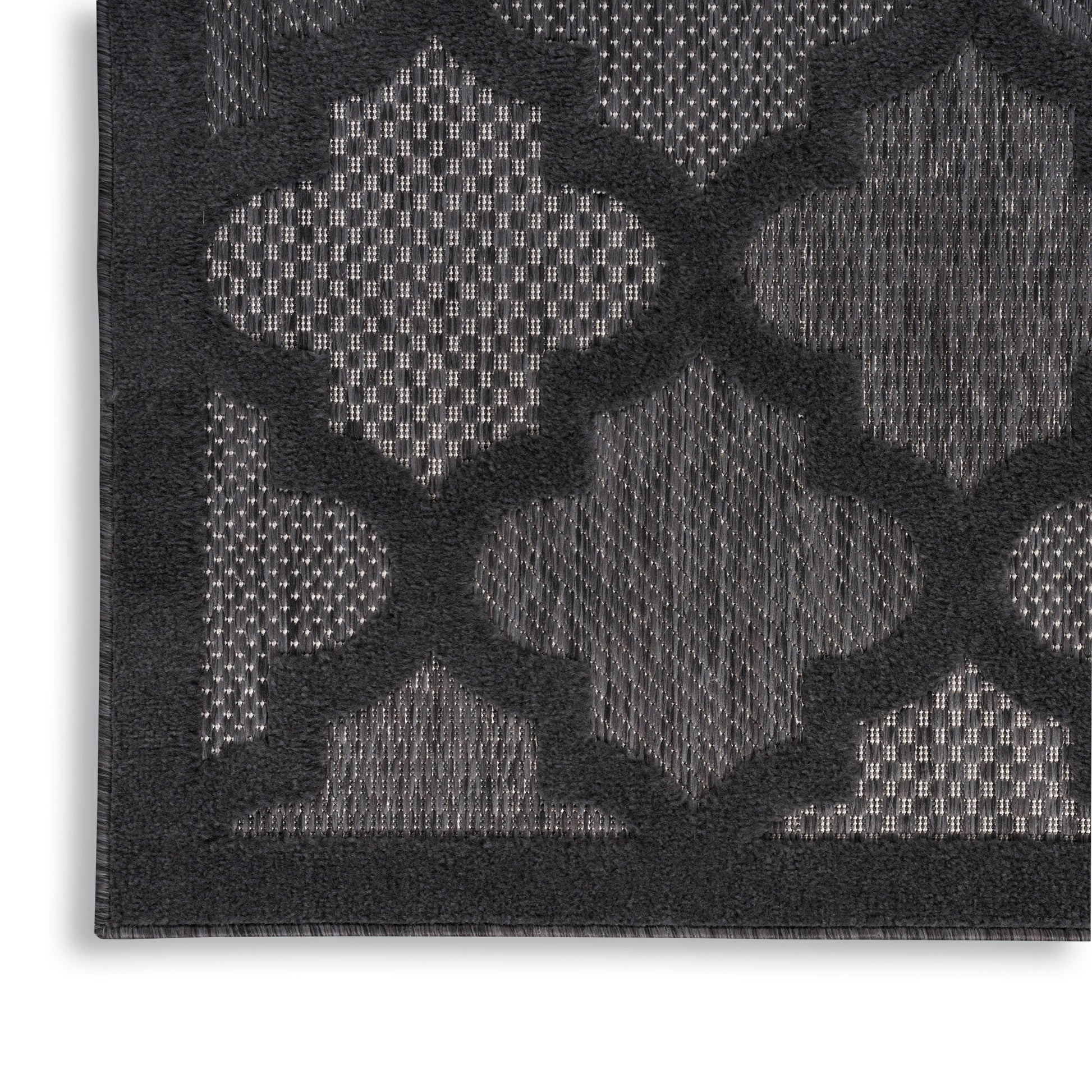 Close-up of a dark charcoal rug with a raised geometric trellis pattern in lighter gray tones.