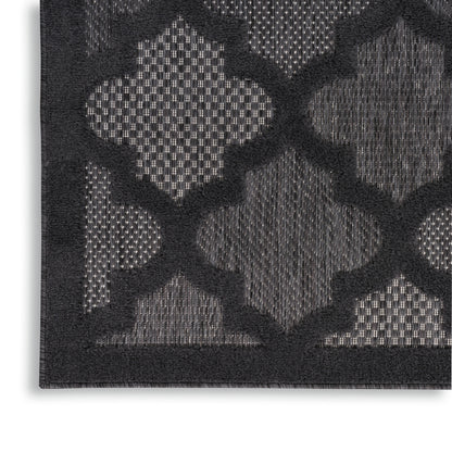 Close-up of a dark charcoal rug with a raised geometric trellis pattern in lighter gray tones.