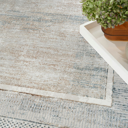 Light gray-blue rug with subtle geometric border; white tray holds a green leafy plant in a terracotta pot.