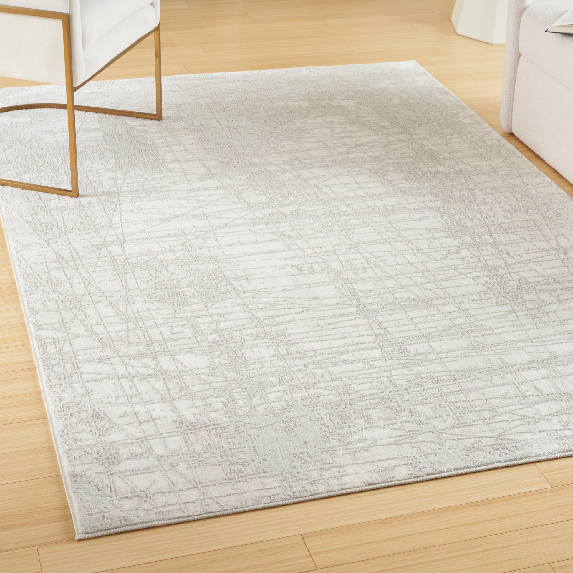 Rectangular light-gray modern area rug with soft pile and abstract crosshatched pattern on warm wood floor.