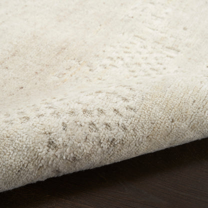 Close-up of a light beige textured rug with dense short loops on a dark wooden floor.