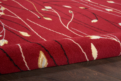 Red plush area rug with white wavy lines and cream-yellow leaf accents, rolled edge on dark wooden floor.