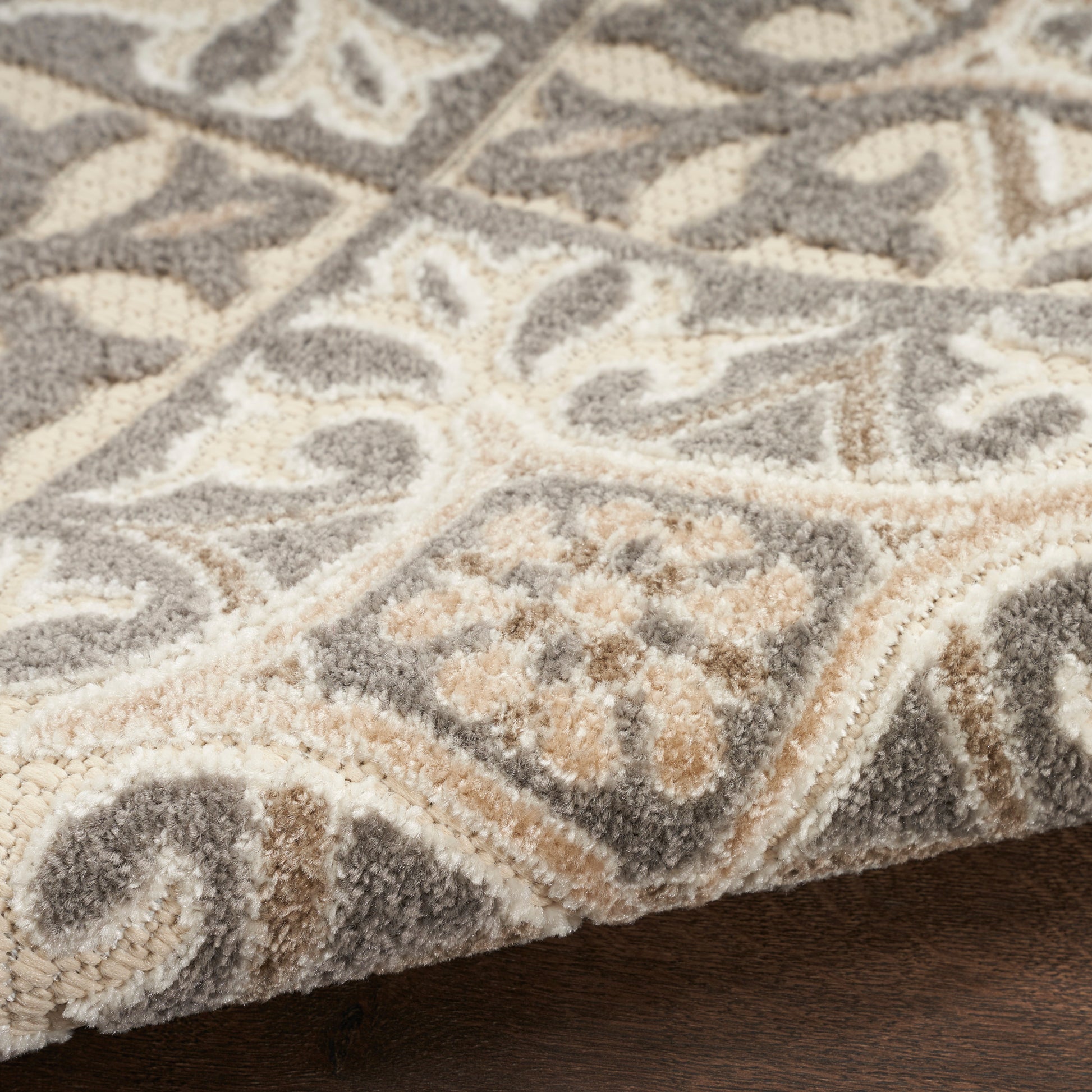 Neutral grey and beige patterned round rug with ivory scroll motifs, bordered plush high-pile rug.
