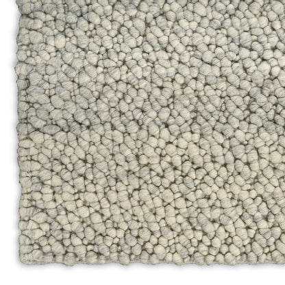 Cream boucle rug close-up with dense rounded loop pile in light gray-beige, soft chunky texture.