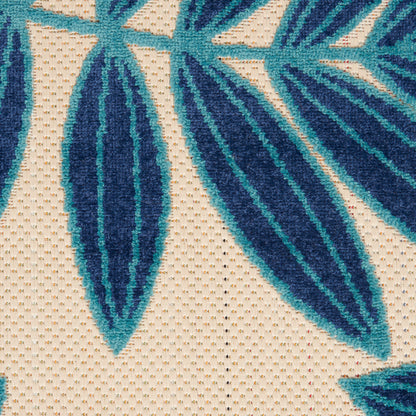 Beige woven fabric with bold teal-blue tropical leaf pattern; large elongated leaves for upholstery or throws.