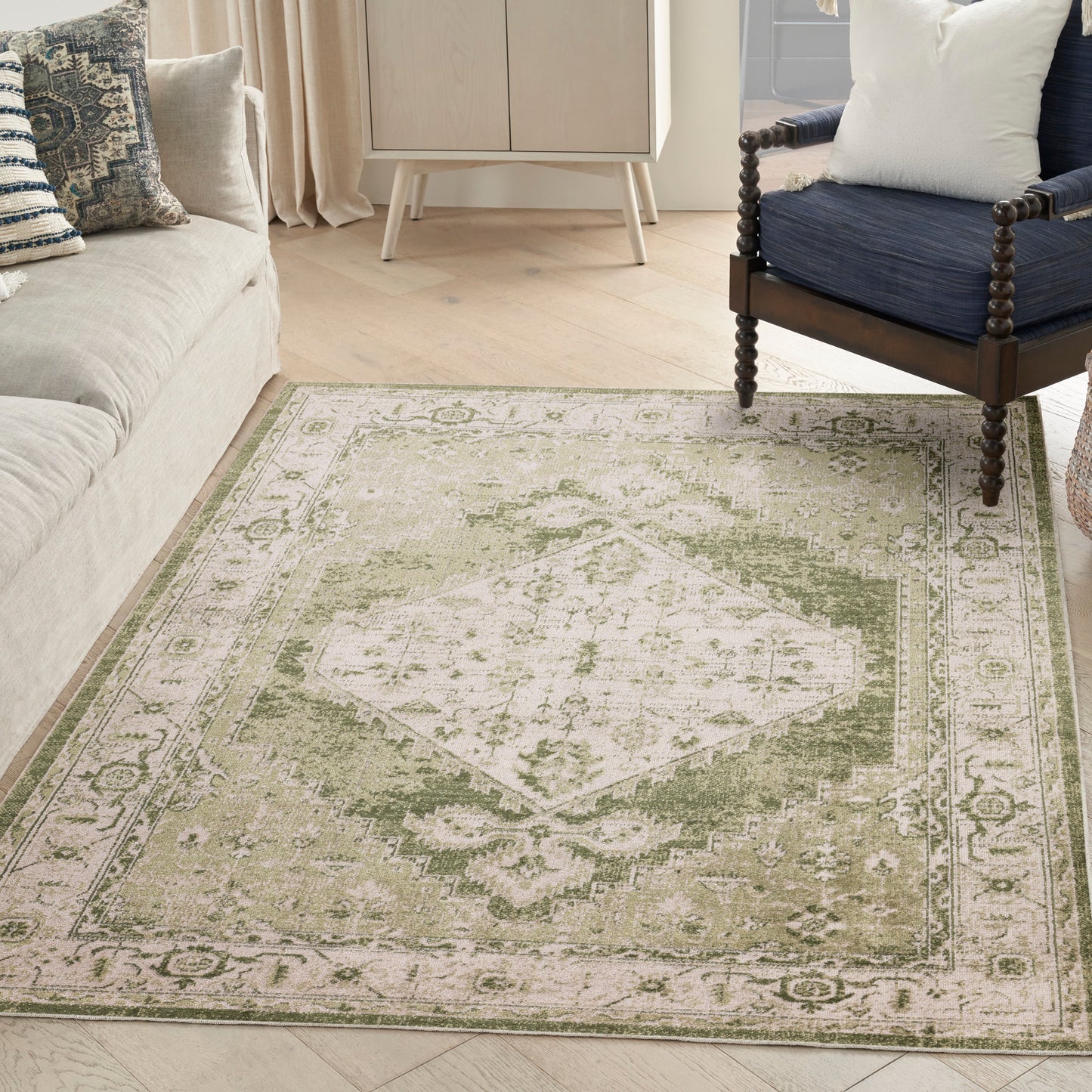 Olive-green and cream area rug with central diamond medallion and ornate border in a cozy living room.
