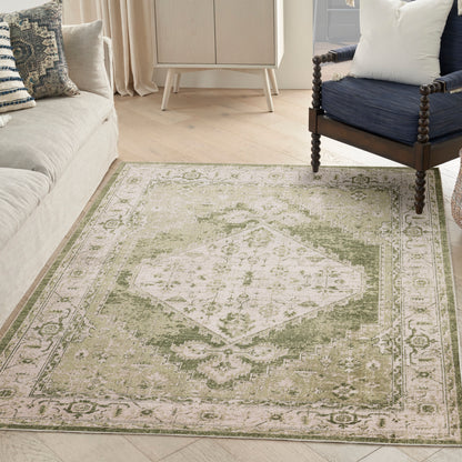 Olive-green and cream area rug with central diamond medallion and ornate border in a cozy living room.