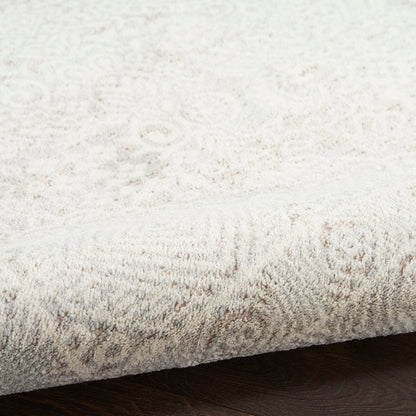 Creamy ivory shag-style area rug with a subtle damask pattern and dense plush pile on dark wood floor.