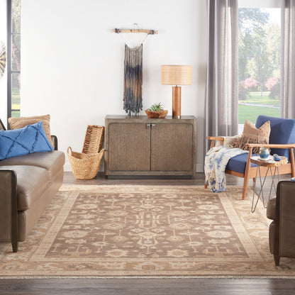 Boho living room with beige patterned rug, brown leather sofas, blue cushions, wicker basket, wood console, lamp, gray drapes.