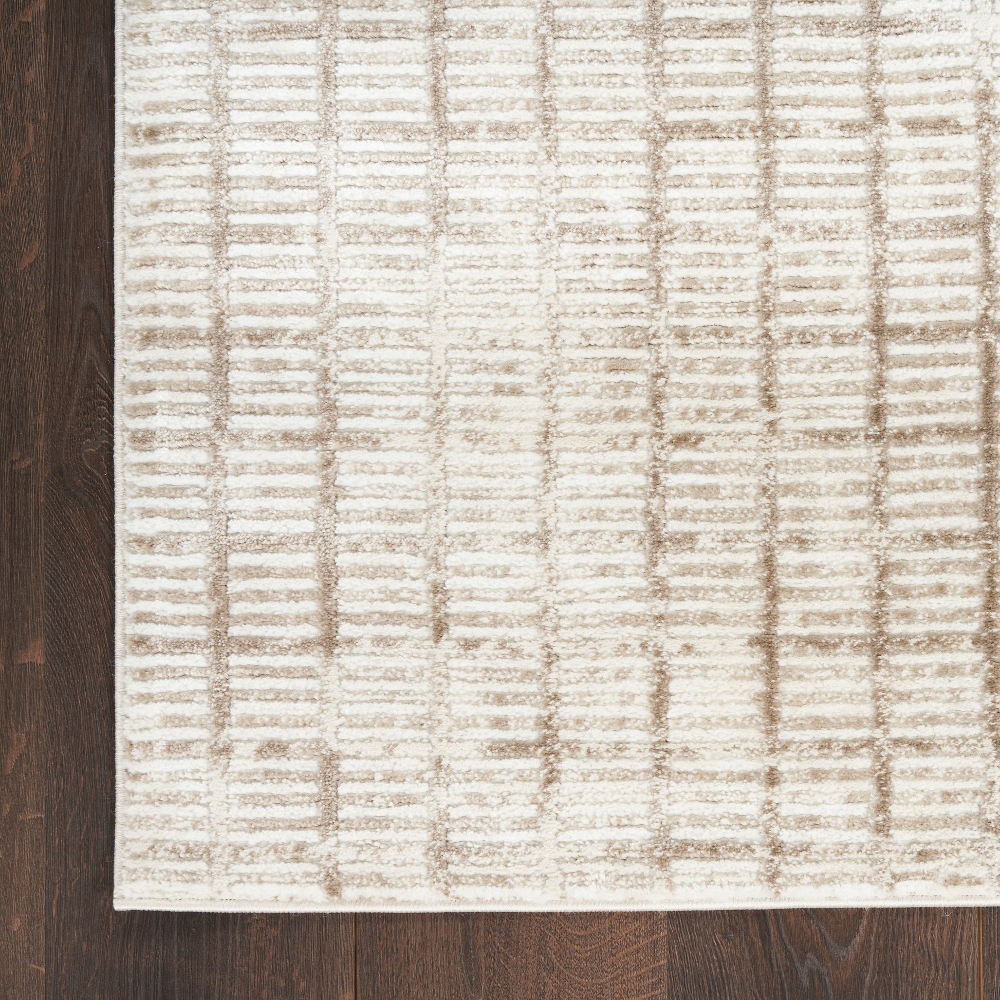 Cream textured area rug with a subtle brown grid pattern on dark hardwood floor.