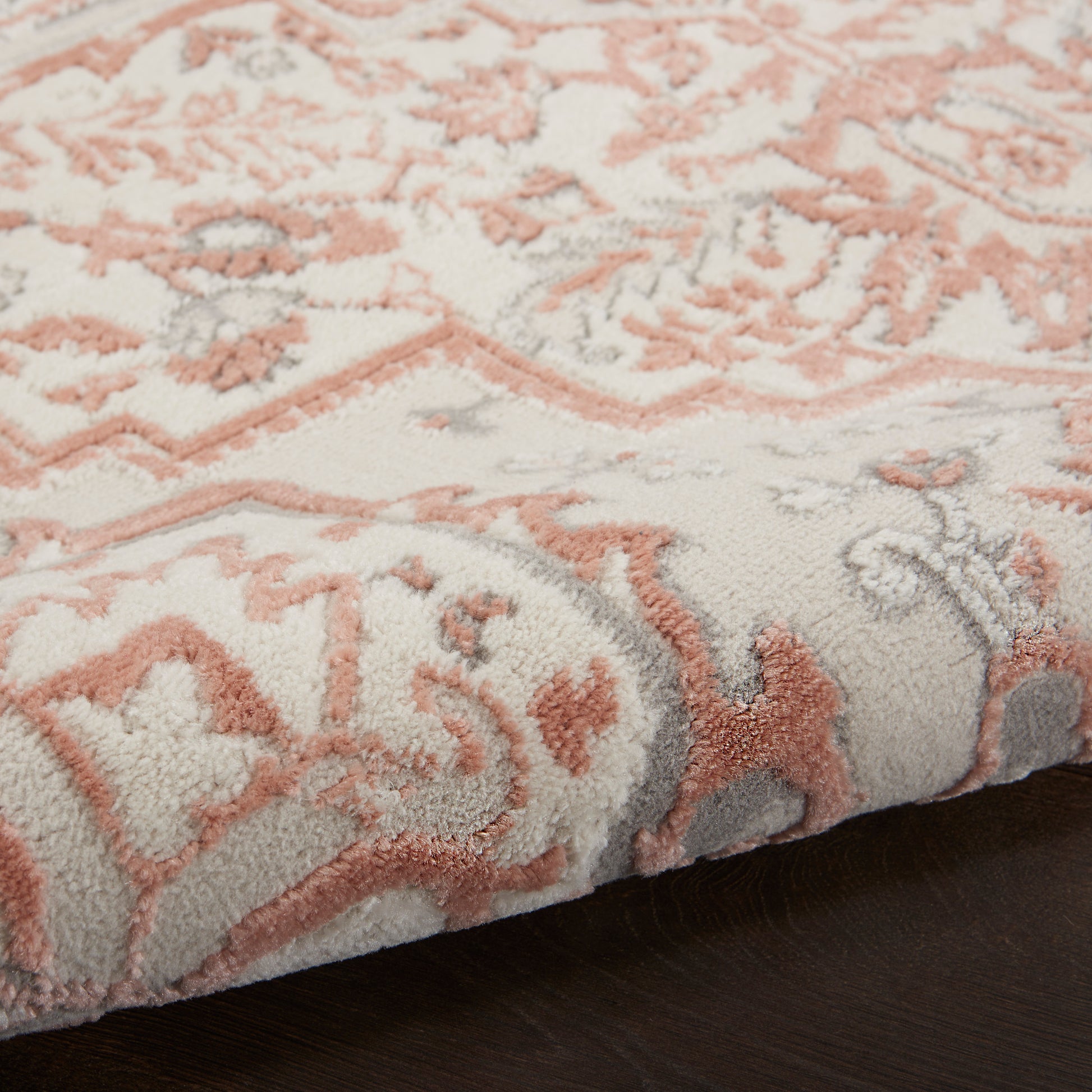 Soft plush area rug with pink peach floral pattern on cream background; textured pile, curled edge, Bohemian style.