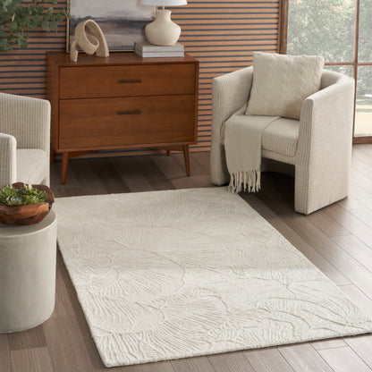 Beige textured area rug with a subtle leaf pattern on wood floor, paired with a mid-century dresser and cream chairs.